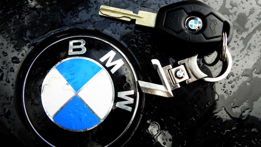 A BMW key sits on the bonnet of a car, next to the BMW logo
