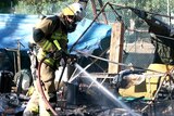 A firefighter extinguishes a blaze that destroyed the Aboriginal tent embassy in Musgrave Park.
