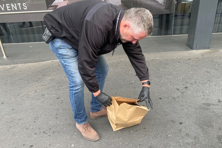 Un homme met sa main dans une poubelle