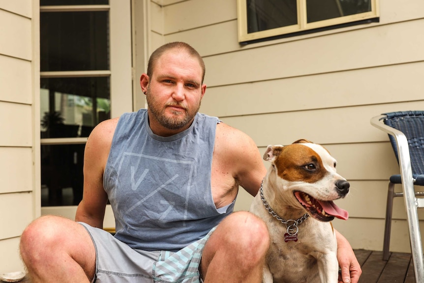 A guy sits on a stoop with his dog