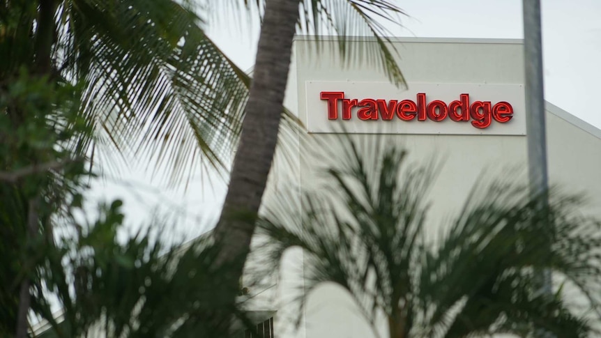 The red sign for the Travelodge motel in Darwin's CBD, with some palm trees visible in the foreground.