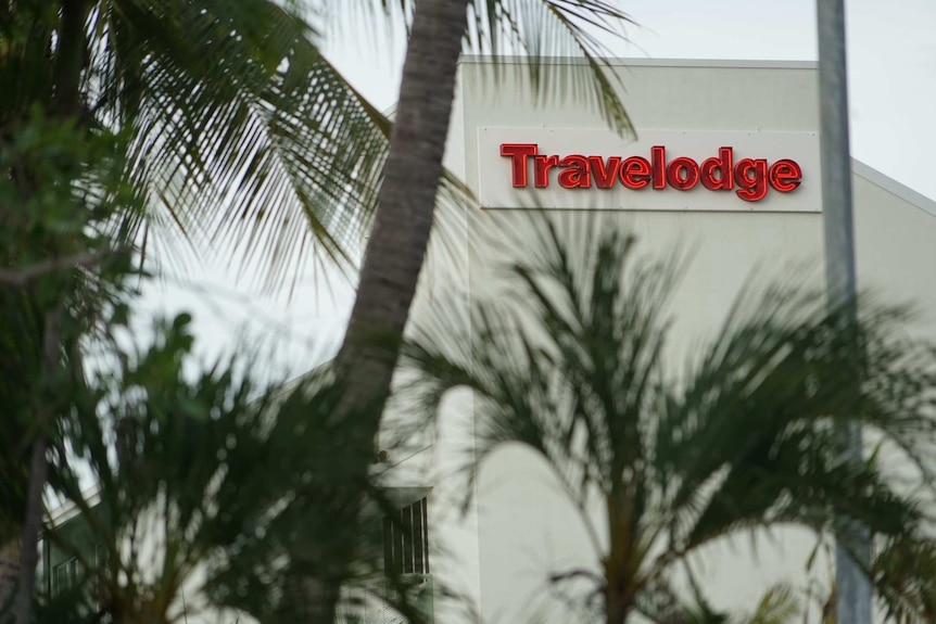 The red sign for the Travelodge motel in Darwin's CBD, with some palm trees visible in the foreground.