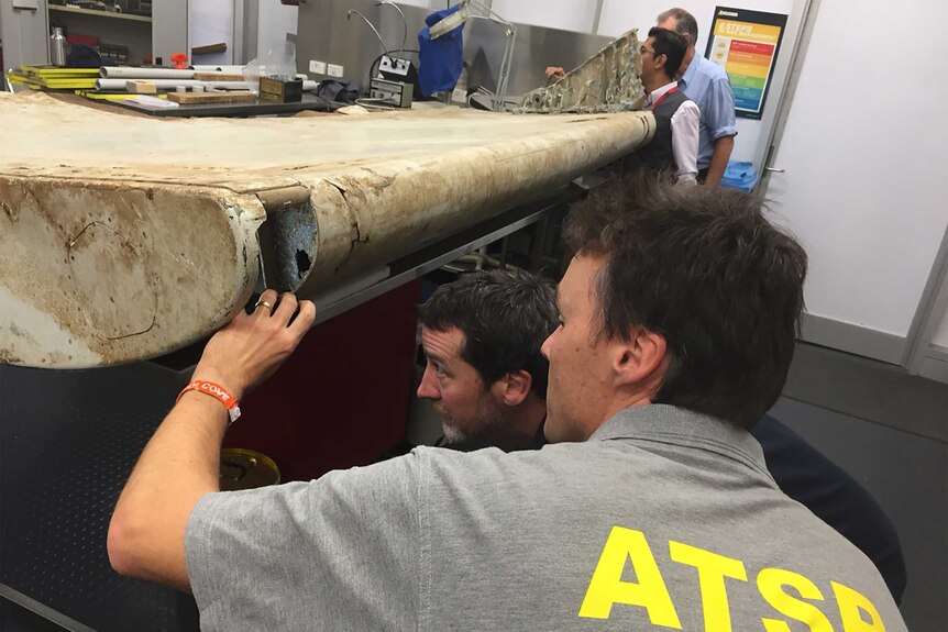 Malaysian and Australian investigators examining a piece of aircraft debris