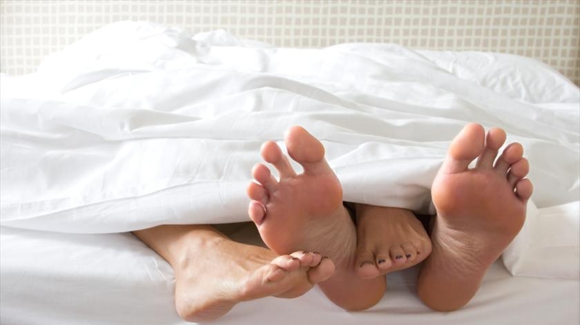 A couple in bed with feet hanging out