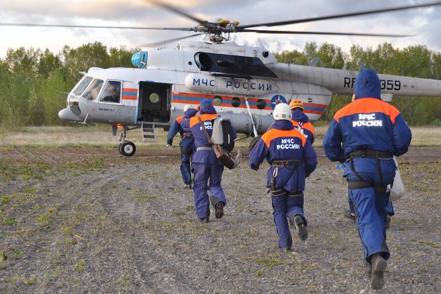 Los equipos de rescate corrieron hacia un helicóptero que estaba a punto de despegar.