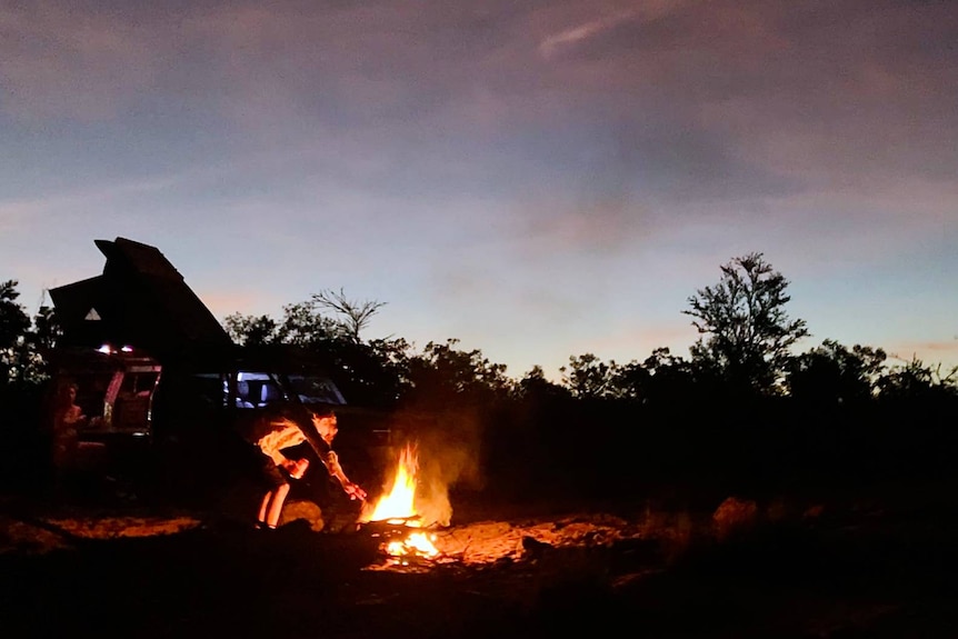 A person tends to a campfire near a camp.