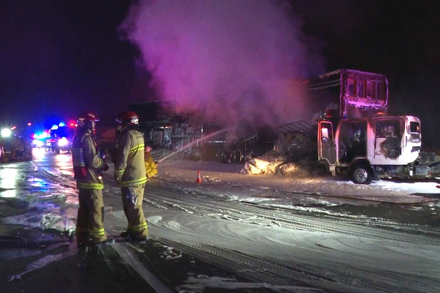 firefighters hosing down a smouldering line of trucks