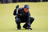 Phil Mickelson lines up a putt in rain