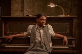 A scene from Ma Rainey's Black Bottom with Chadwick Boseman as a blues musician leaning against a piano