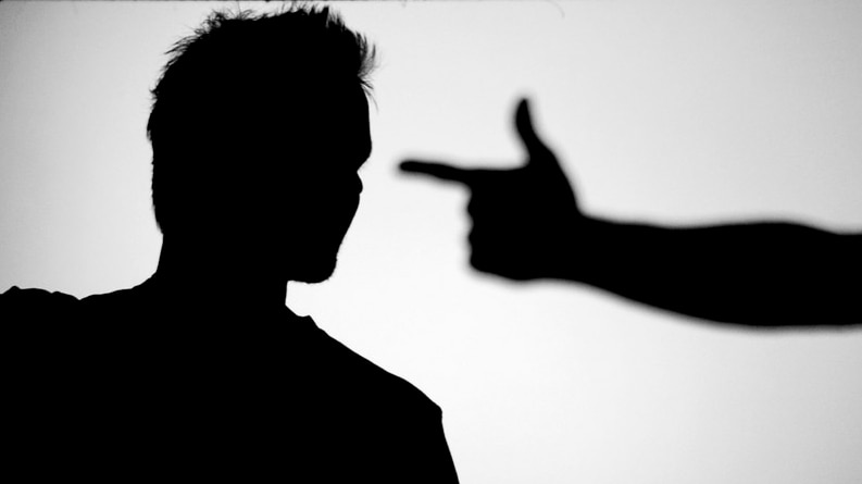 A silhouette of a person making the shape of a gun with their hand