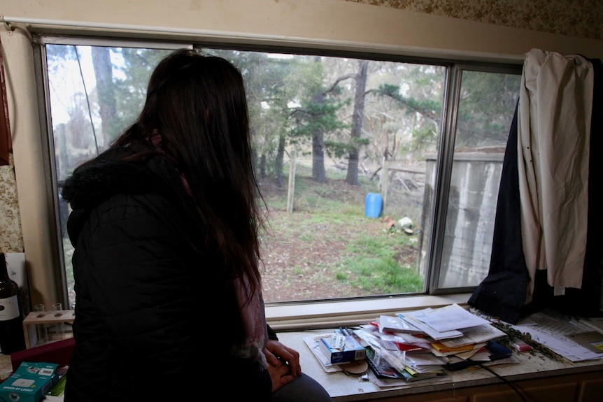 Former sex worker Anna sits at the window inside her home.