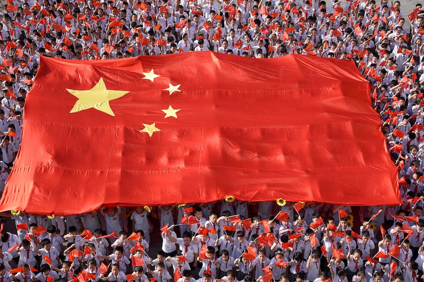 Primary school students hold a giant Chinese flag