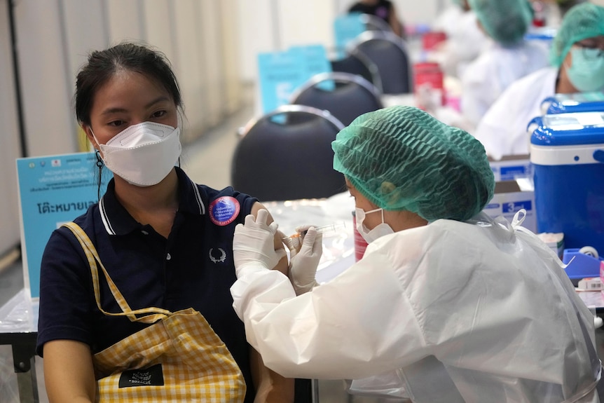 A health worker administers a dose of the Sinovac COVID-19 vaccine to a woman in Bangkok