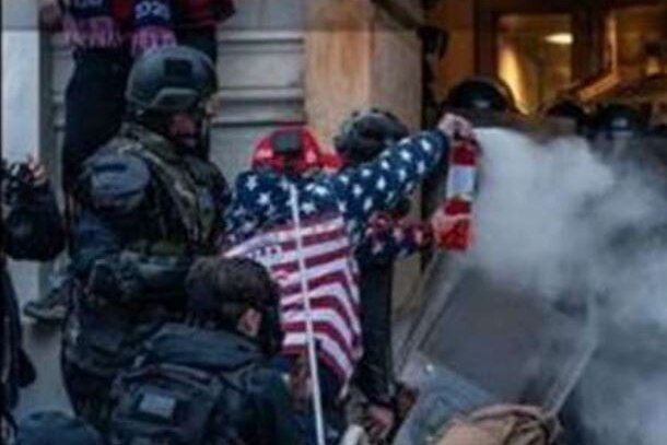 Robert Scott Palmer dressed in an American flag jumper sprays a fire extinguisher toward police during the Capitol riot