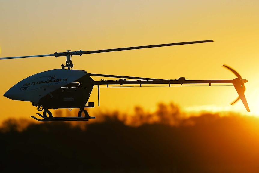 A helicopter drone flies at sunset