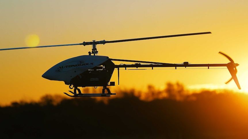 A helicopter drone flies at sunset