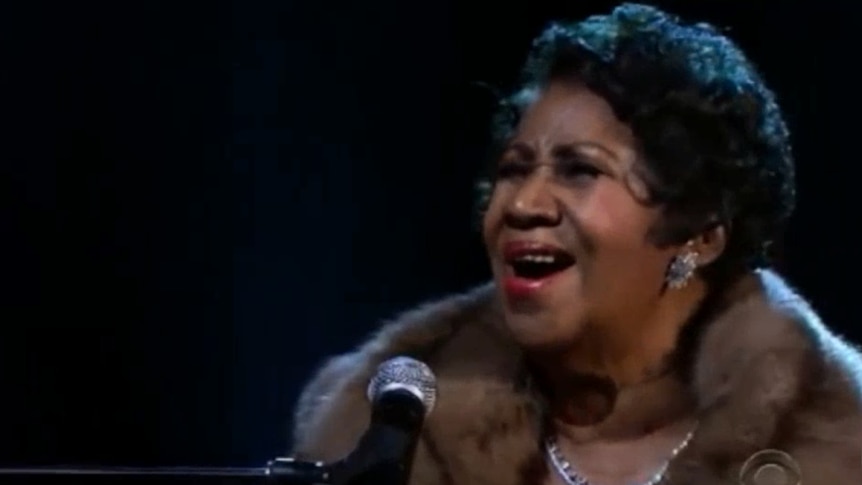 Aretha belts out a note into a microphone