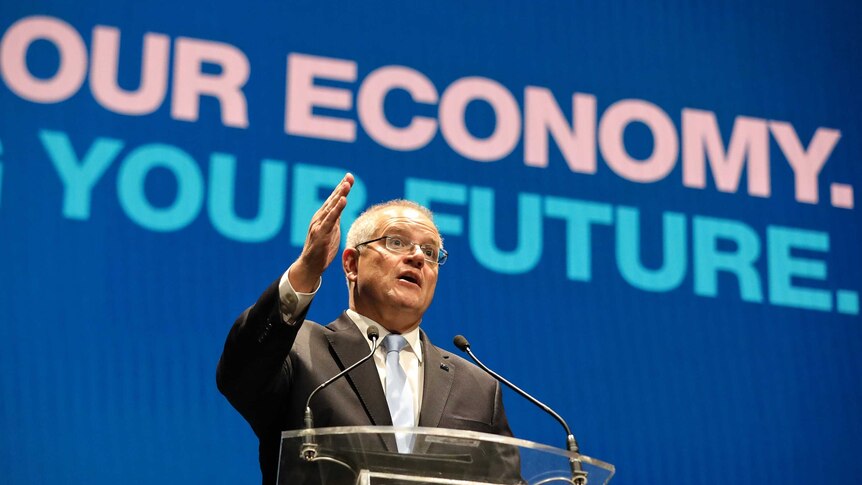 Scott Morrison puts his hand up as he speaks in front of the words "OUR ECONOMY. YOUR FUTURE." at the Coalition campaign launch.