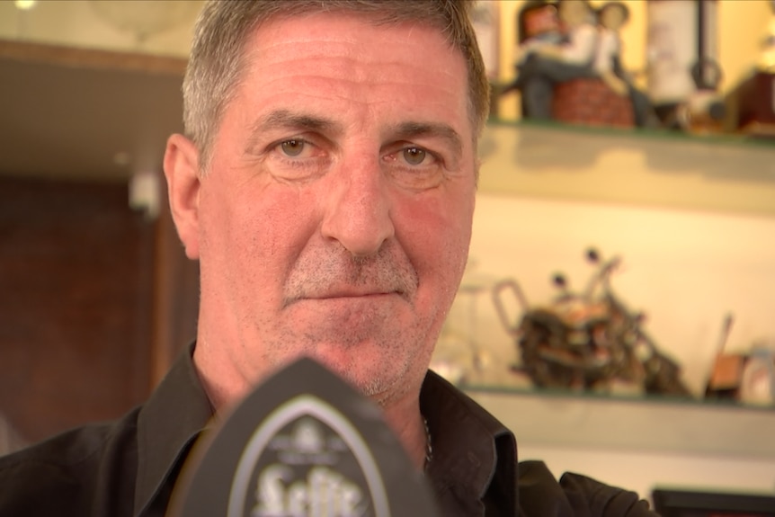 Joseph Sauvage stands behind a beer tap in a pub in the town of denain