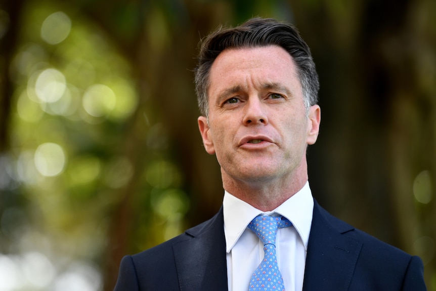 A man wearing a blue tie and dark suit.