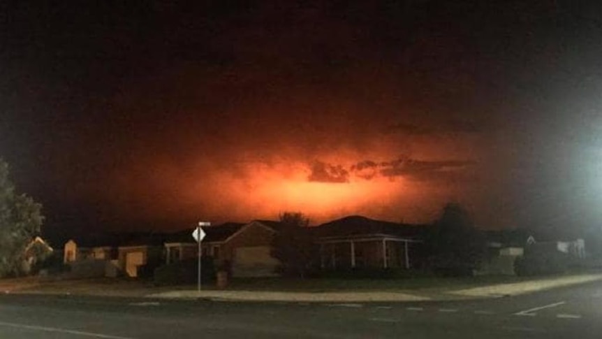 The night sky glows from a fire near a regional town.