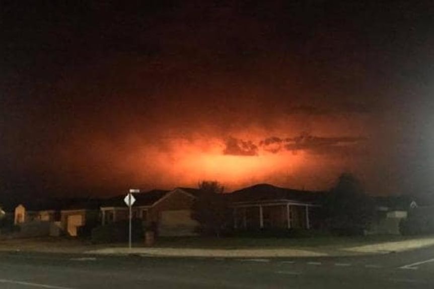 The night sky glows from a fire near a regional town.