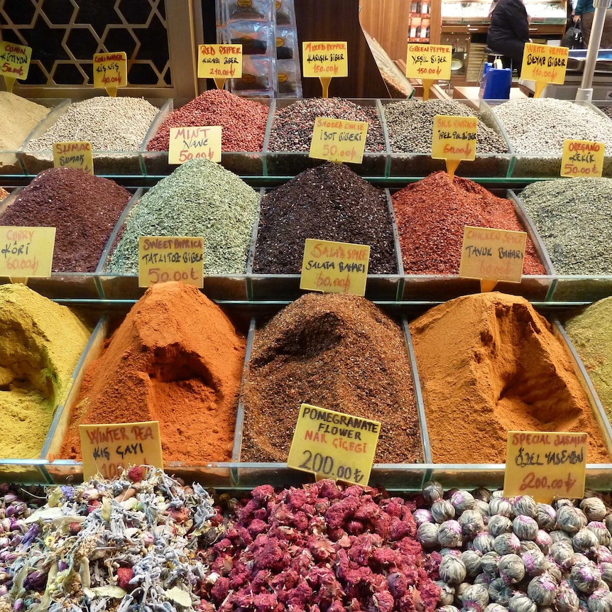 Three rows of various colourful spices piled high in tubs.