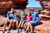 Family of five sitting on a red rock formation. 