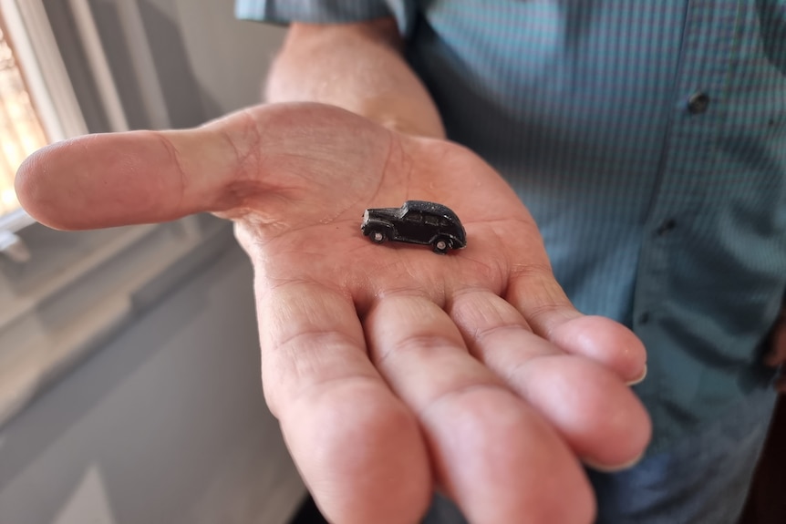 A small black car on the palm of a hand.