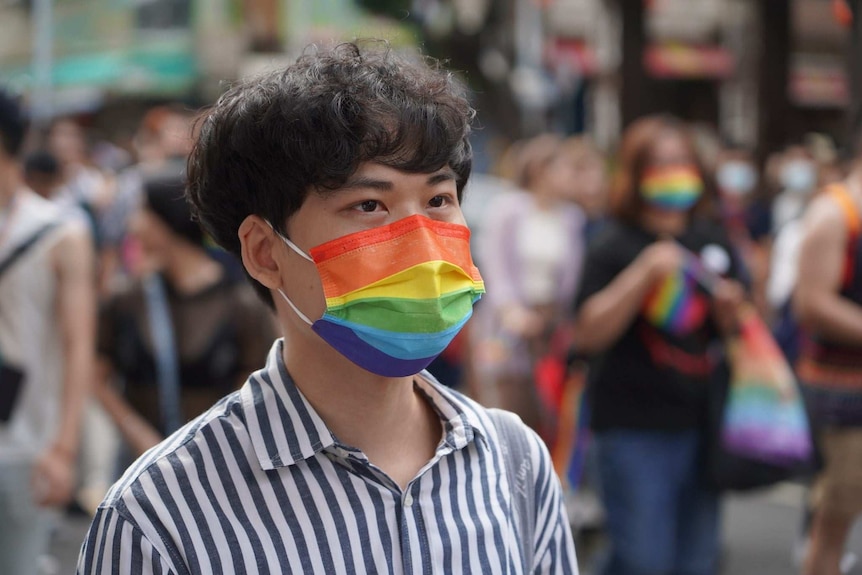 A man wears a rainbow face mask