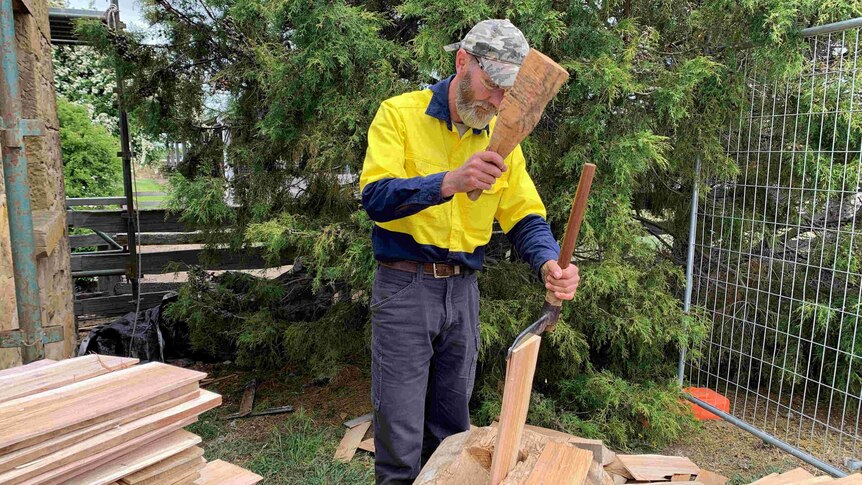 Heritage builder Graham Green using old tools to chop wood for roof shingles