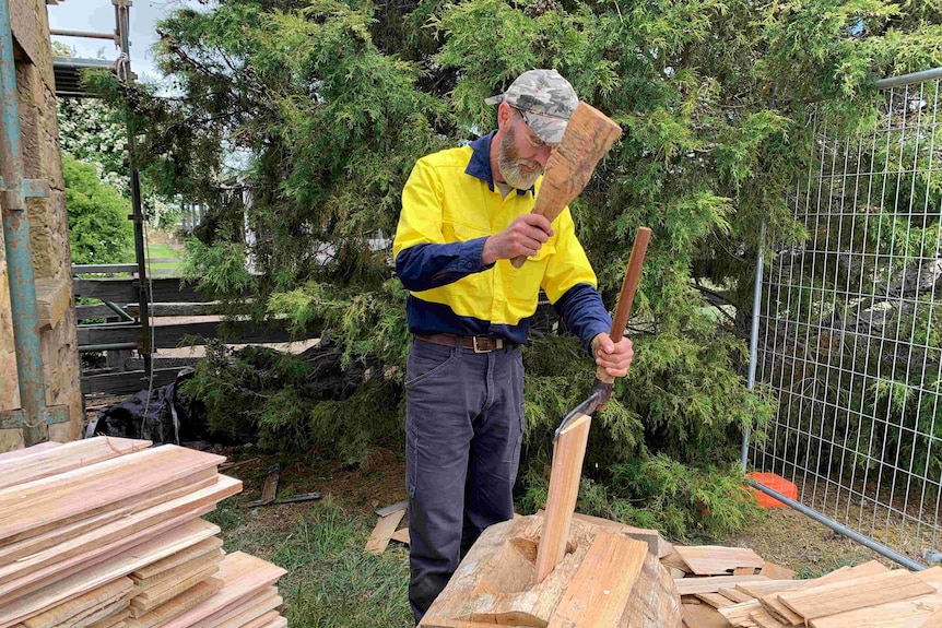 Heritage builder Graham Green using old tools to chop wood for roof shingles