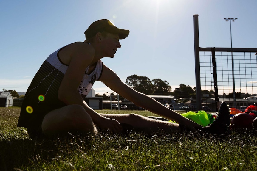 Silhouetted player stretching at football training, Tasmania.