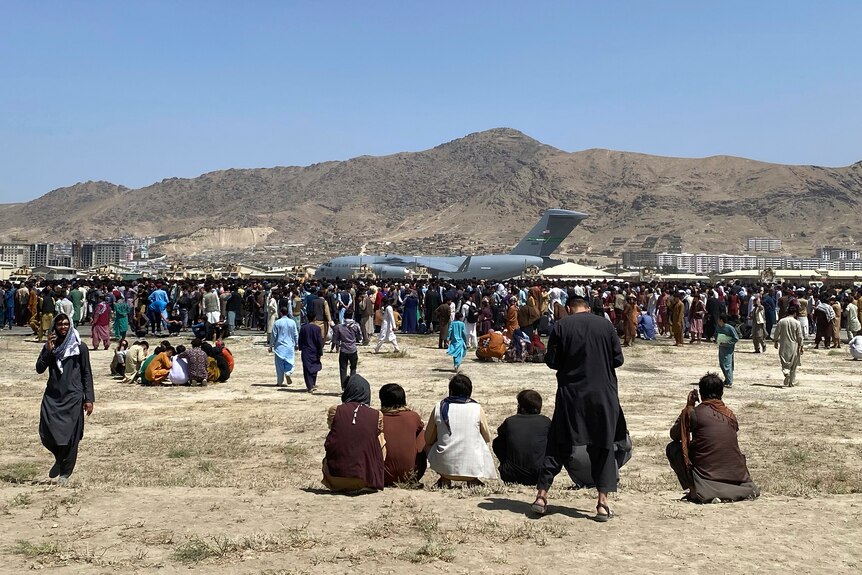Hundreds of people gather near a US transport plane at Kabul airport.
