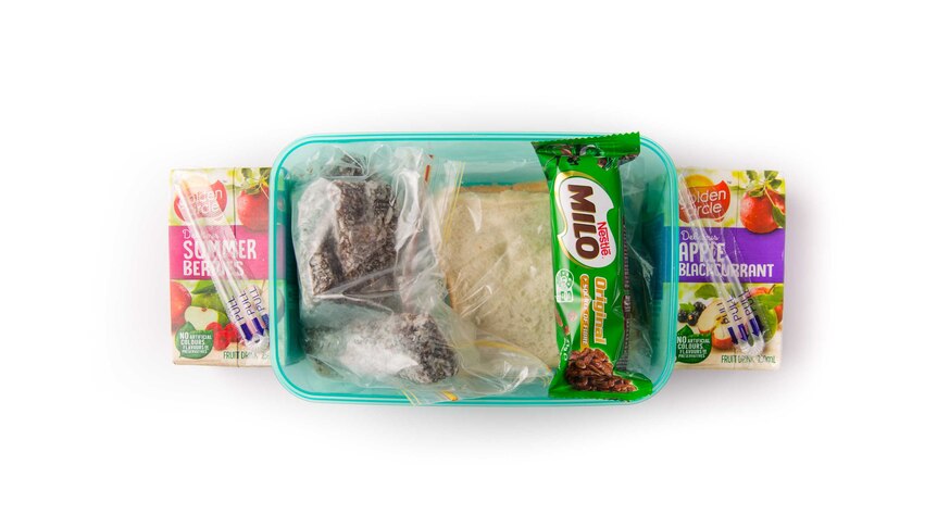 A peanut butter sandwich, lamingtons, chocolate rice puffs bar and two fruit drinks in a clear green lunch box.