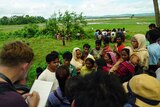 A reporter talks to villagers in the Rakhine region of Myanmar on a government tour of the region, July 2017.