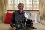 Man holding two old cameras on his lap