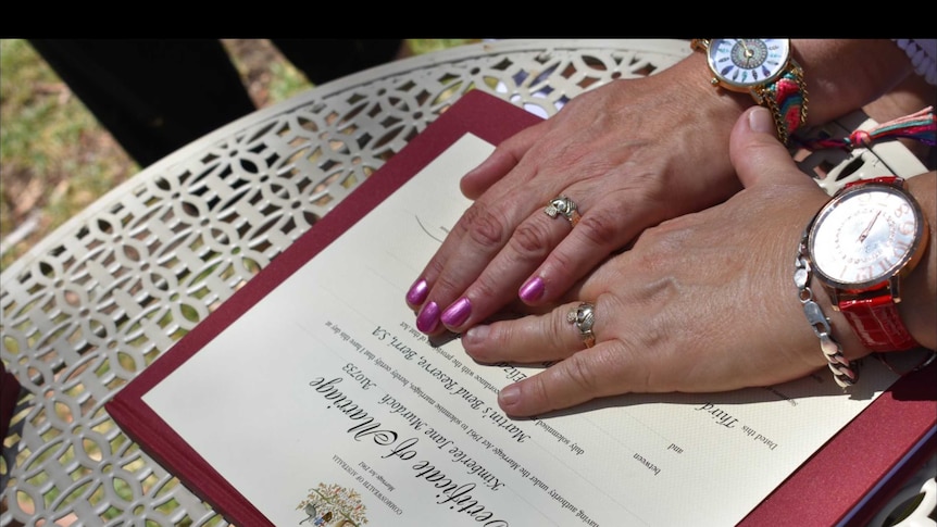 Two female hands together on a marriage certificate.