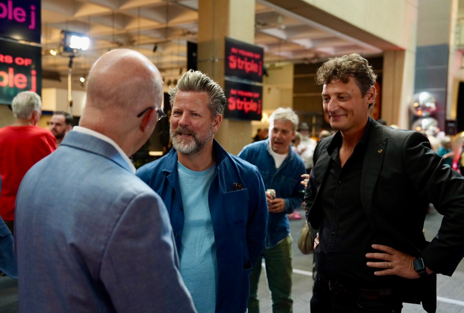 A group of three men engaged in conversation.