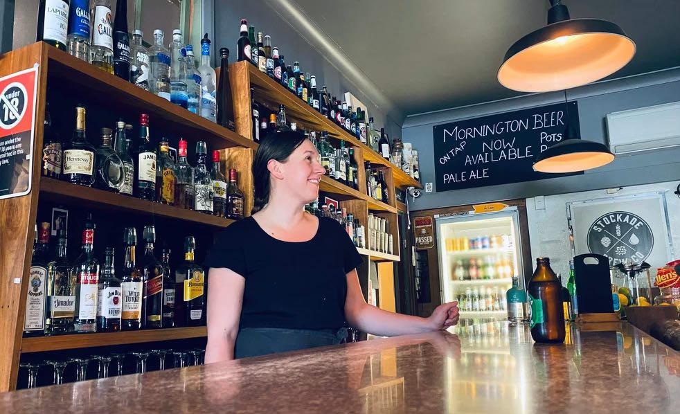 Siobhan, wearing a black t-shirt, works at a bar.