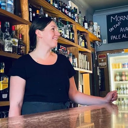 Siobhan, wearing a black t-shirt, works at a bar.