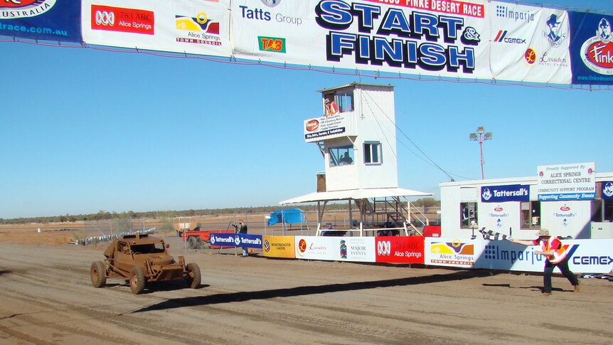 A car covered in mud crosses the Start Finish Line.