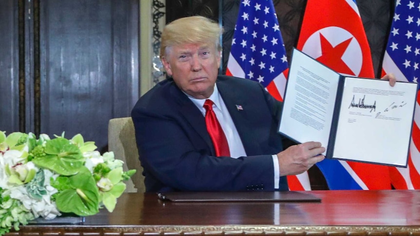 Donald Trump holds up the document that he and Kim Jong-un just signed.