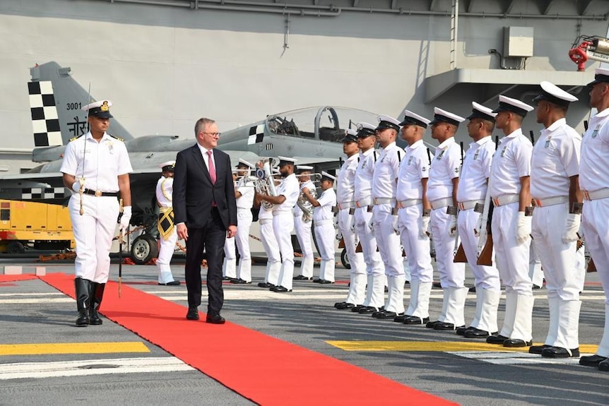 Anthony Albanese walks on red carpet past Indian naval officers on the deck of INS Vikrant.