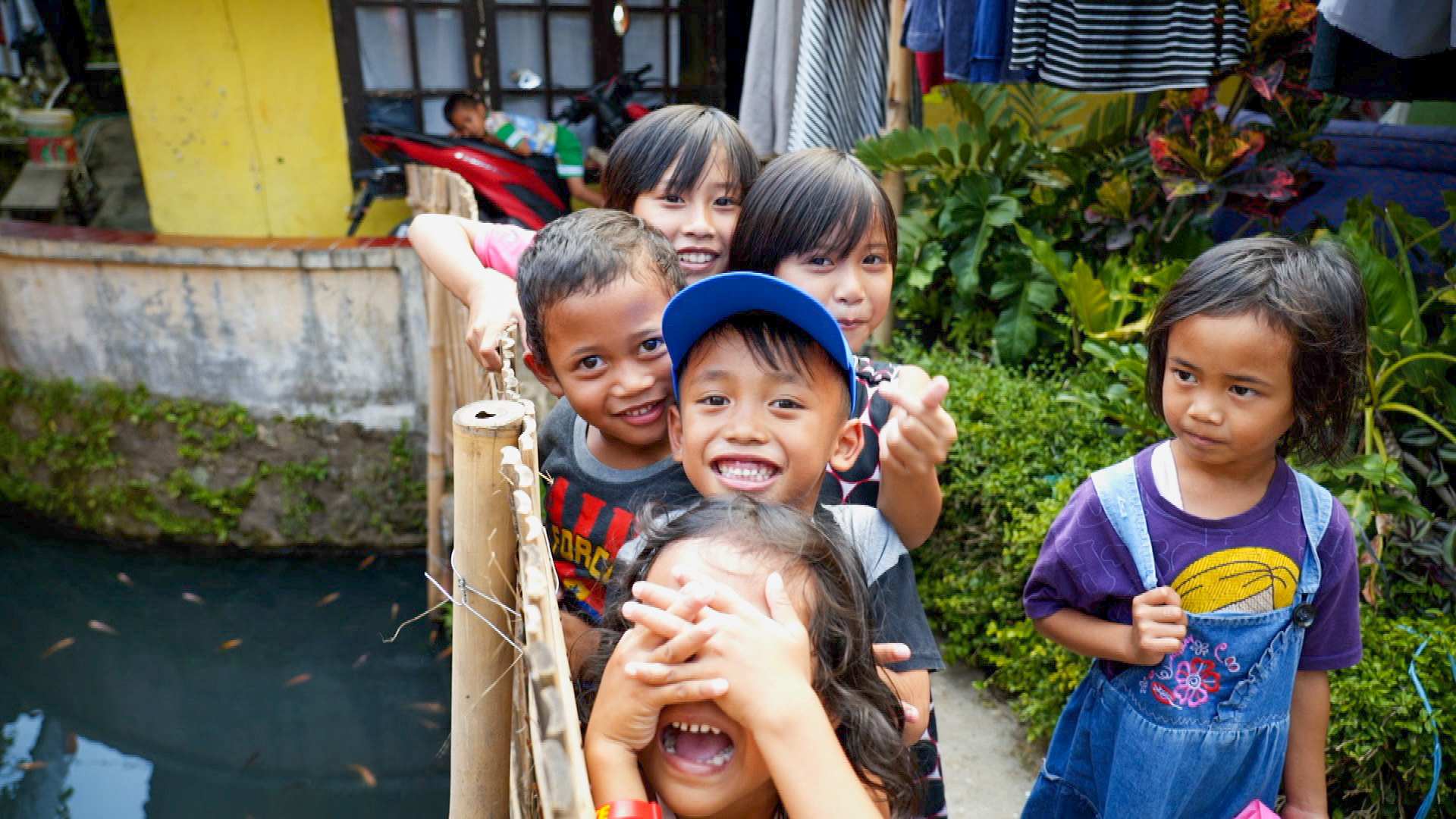 A group of Indonesian children smiling on a bridge