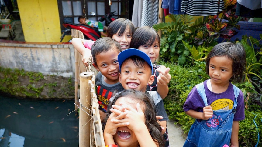 A group of Indonesian children smiling on a bridge
