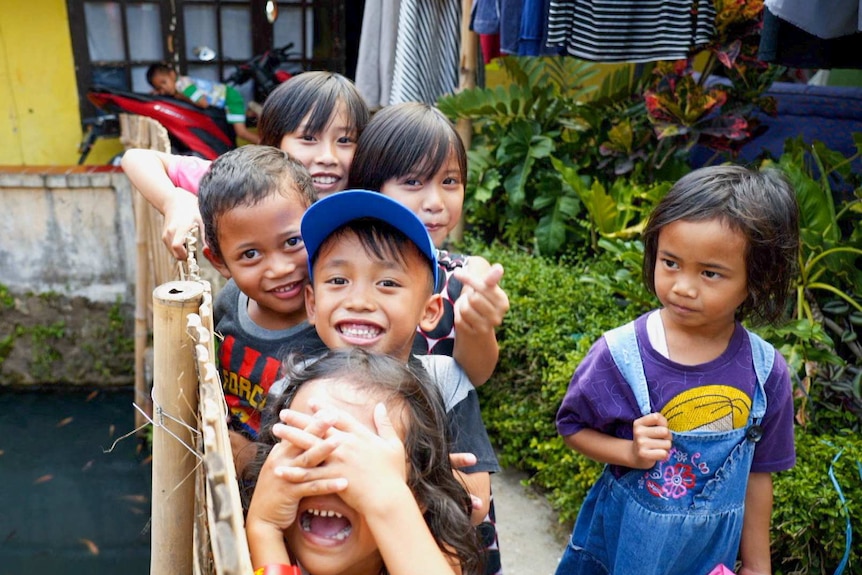 A group of children smiling on a bridge