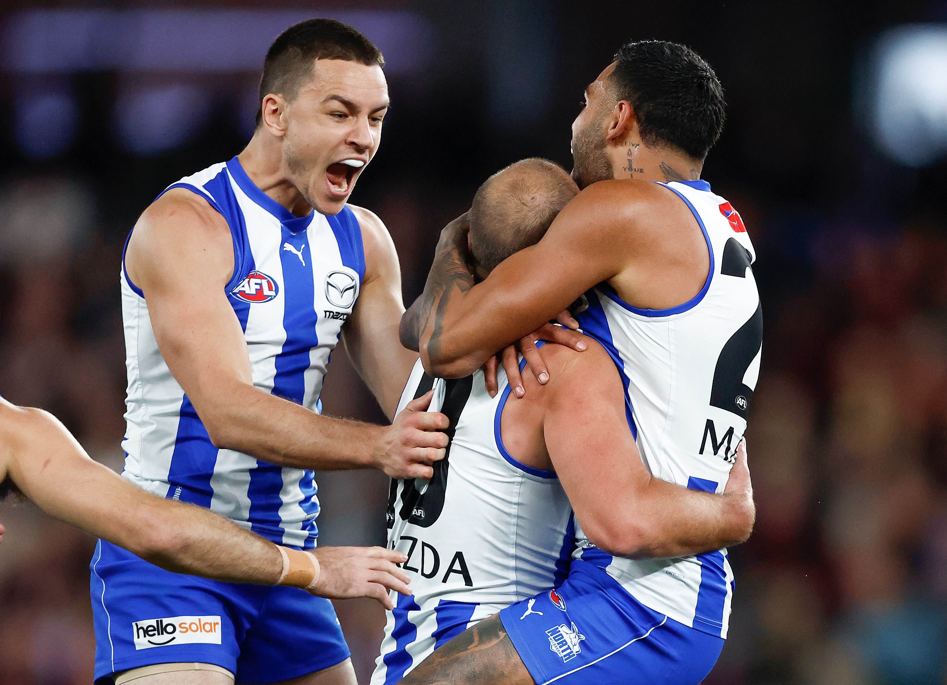 A group of men hug and celebrate a goal.