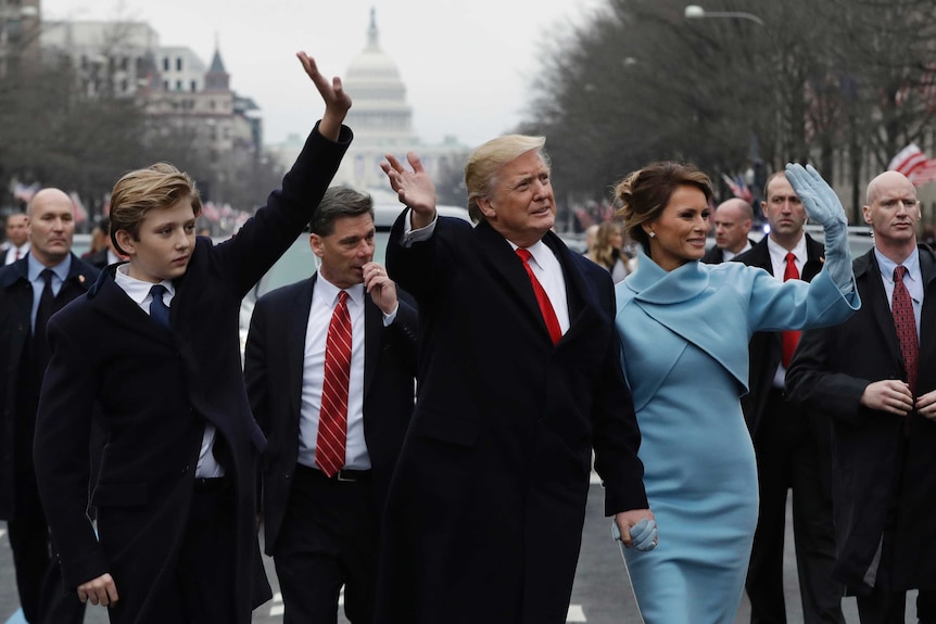 President Donald Trump waves as he walks with first lady Melania Trump and their son Barron during inauguration parade.