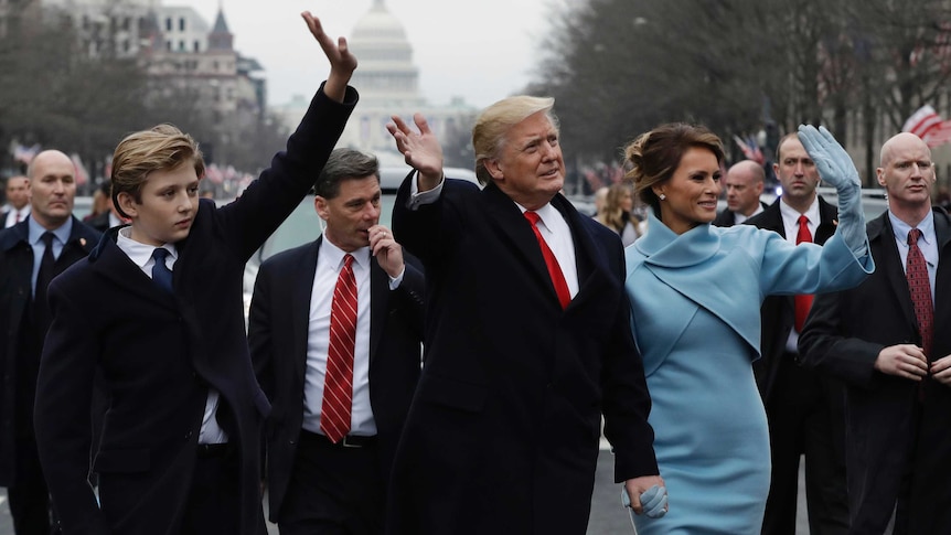 President Donald Trump waves as he walks with first lady Melania Trump and their son Barron during inauguration parade.